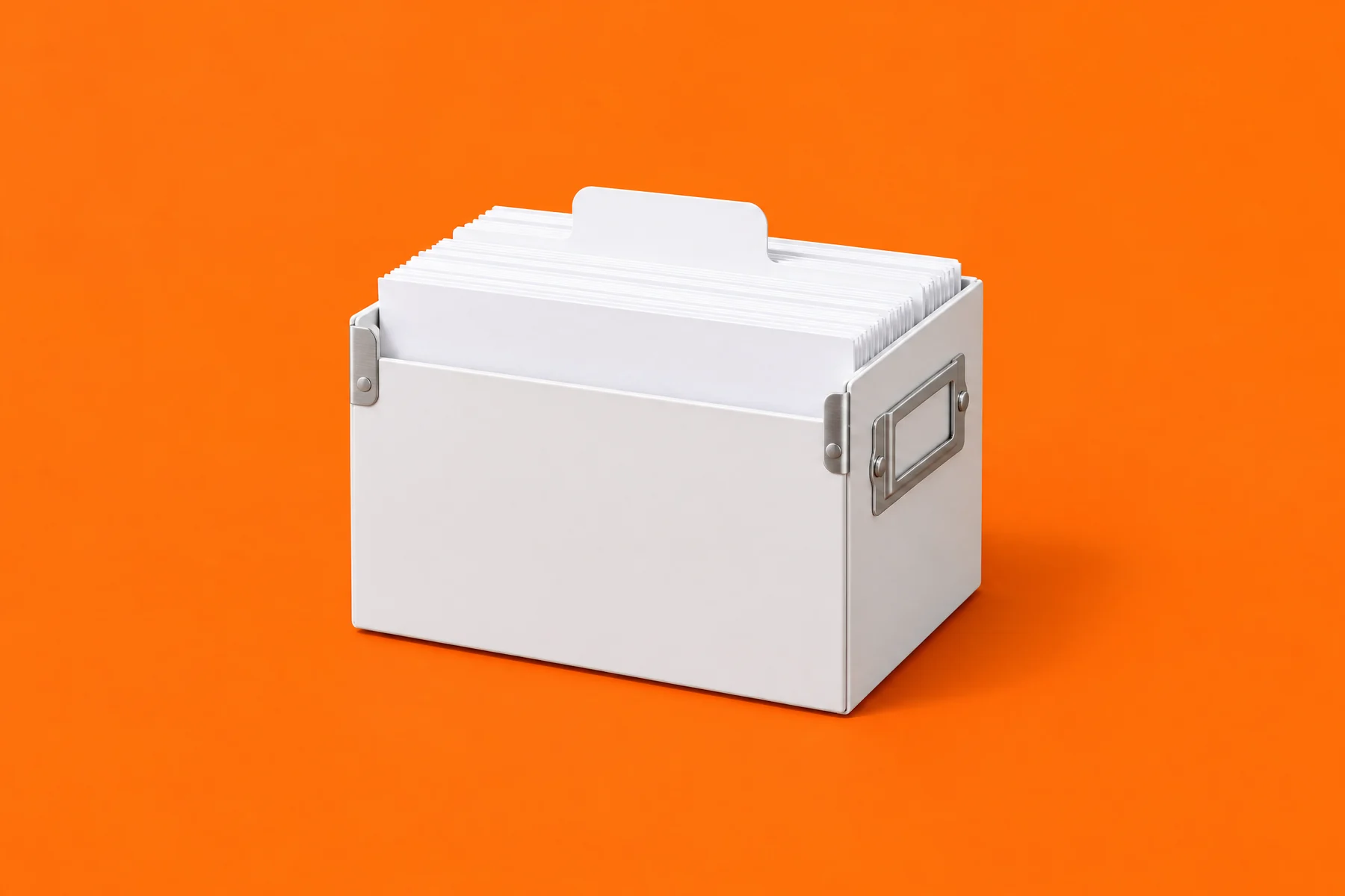 Un bac à fiches blanc aux poignées de métal, rempli de fiches vierges, un intercalaire blanc qui dépasse, sur un fond orange vif.