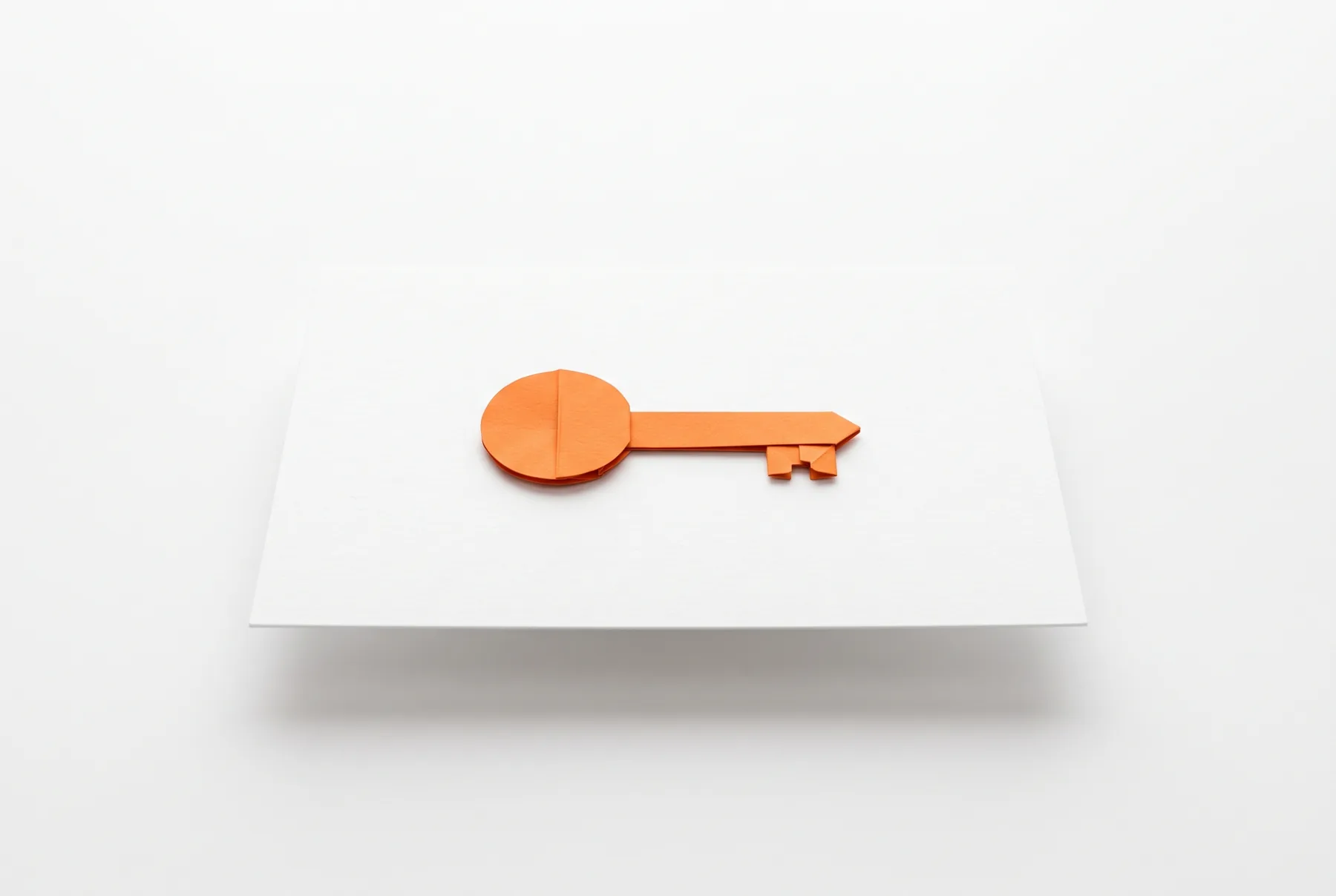 Une clé en papier orange posée sur une feuille blanche.