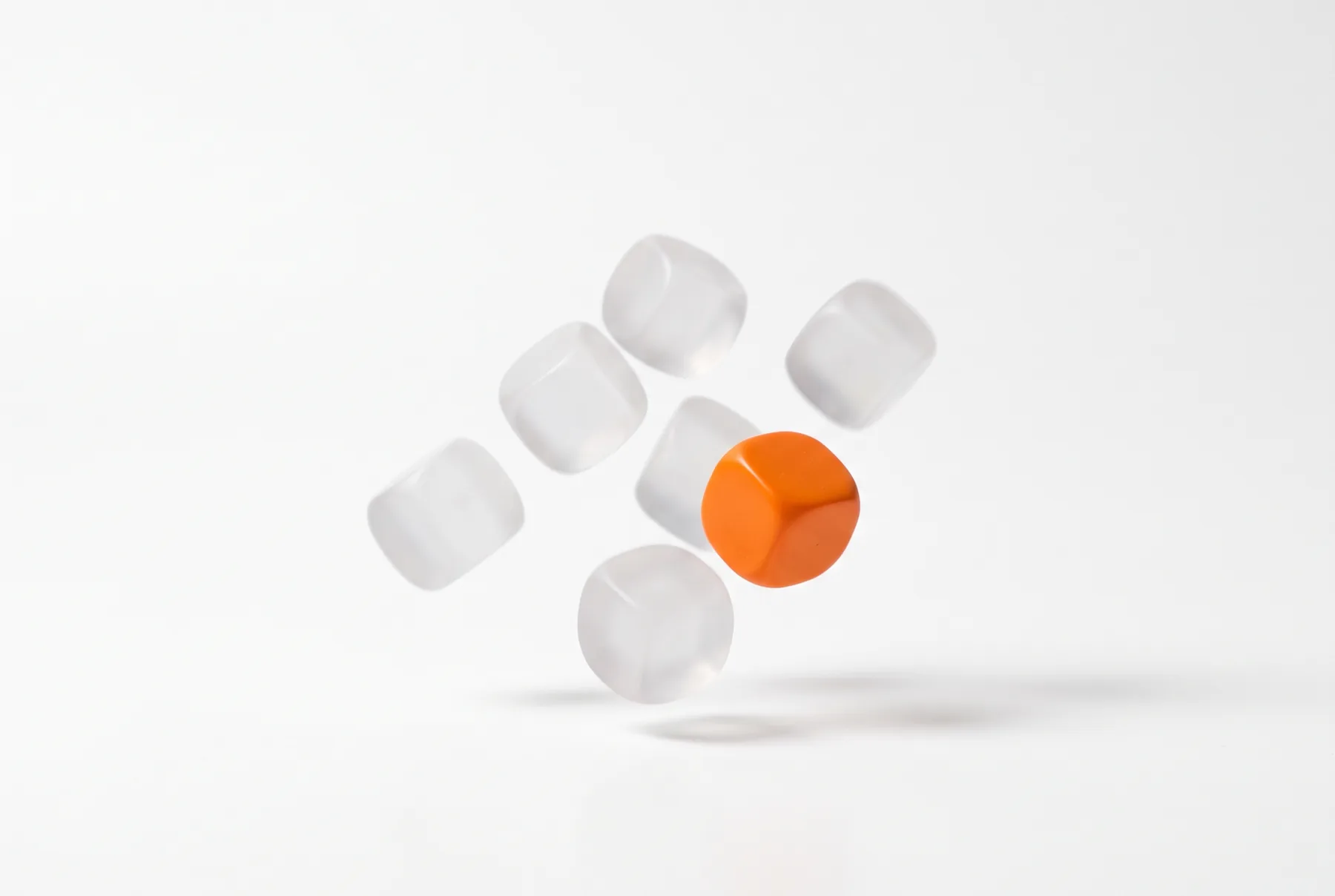 Des dés sans points en suspension : des dés blancs translucides et un dé orange.